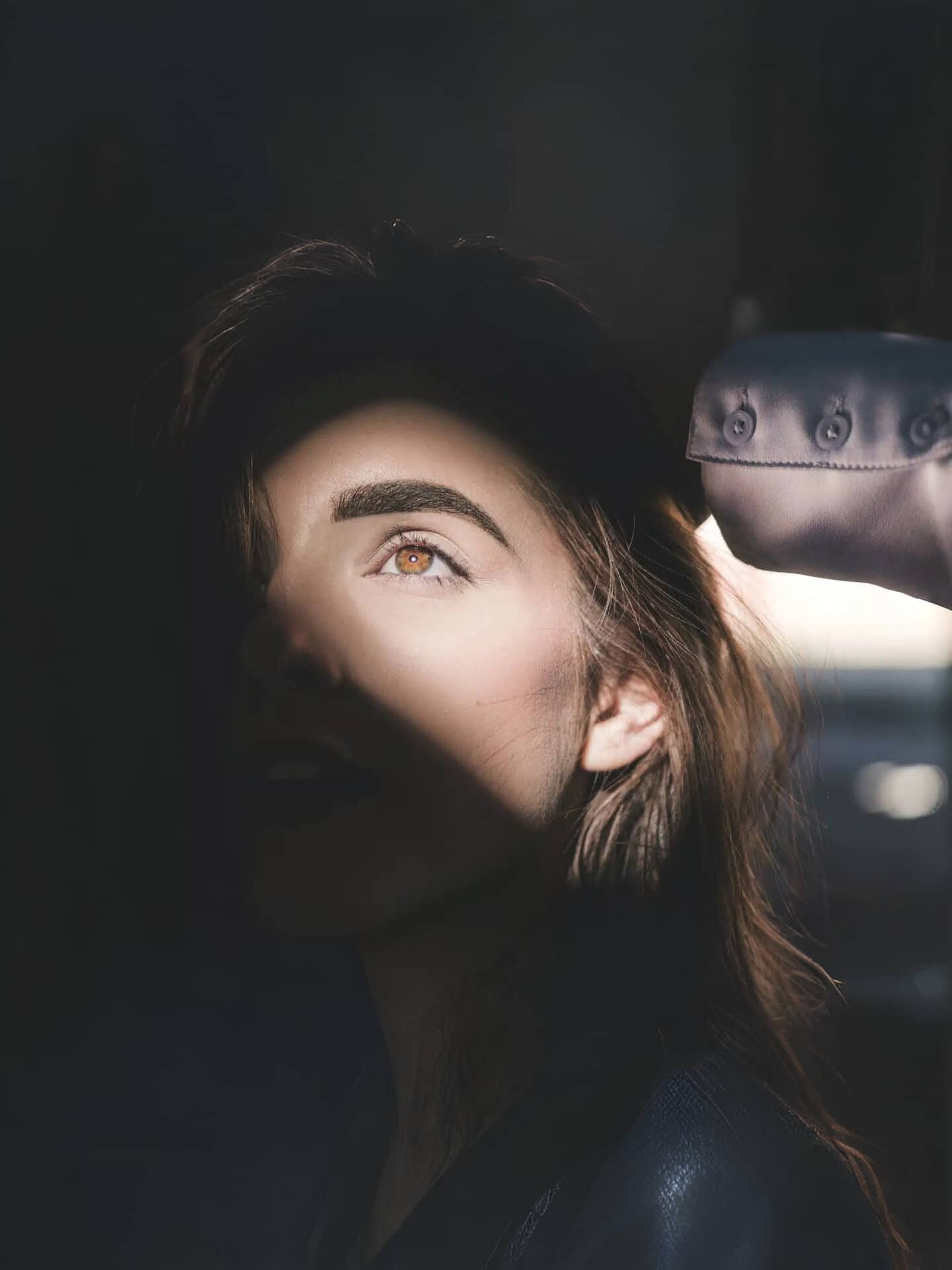 une femme avec un rayon de soleil mettant en évidence une partie de son visage et ses sourcils dessinés